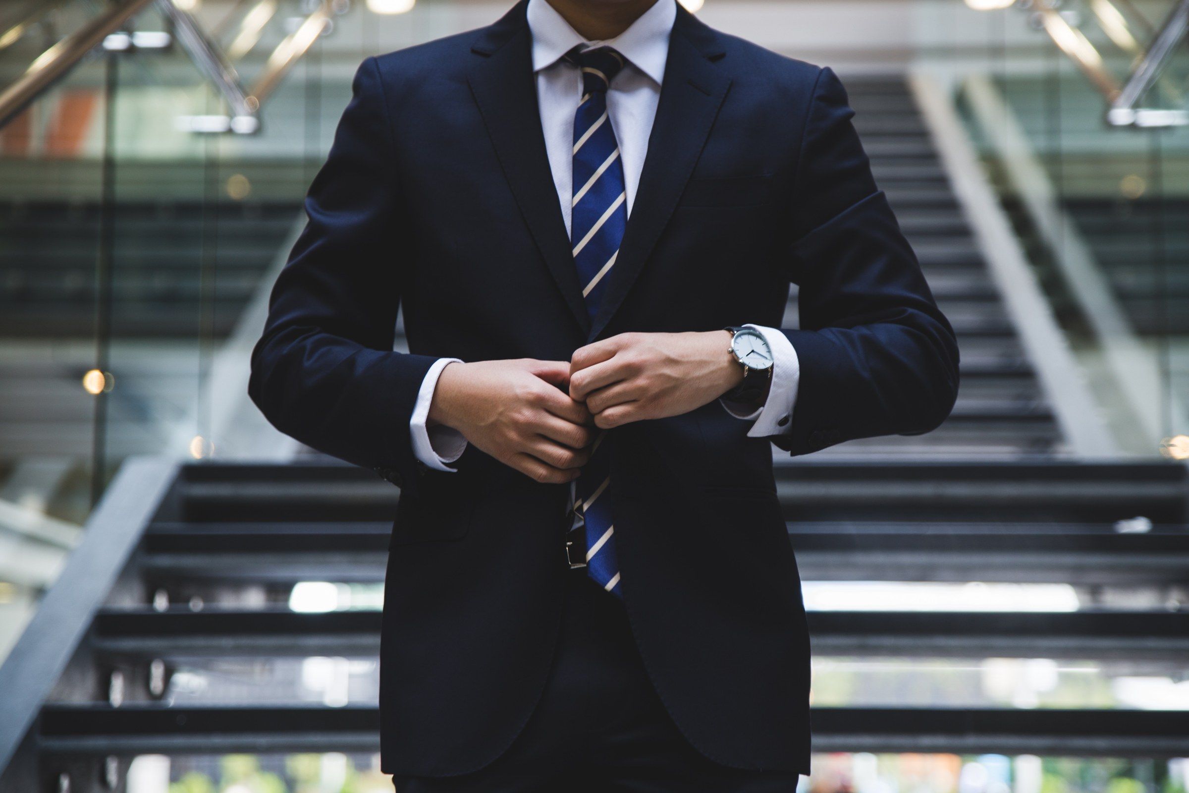 Homme en costume sombre ajustant le bouton de sa veste